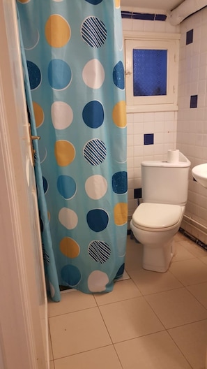 Une salle de bain équipée de toilettes, d’un lavabo et d’un rideau de douche à motifs à pois.