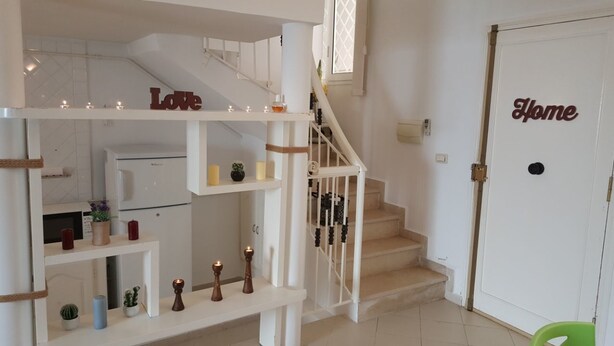 Una escalera con un cartel que dice 'Love' en la parte superior, que conduce a una plataforma con una puerta blanca que lleva la etiqueta 'Home'.