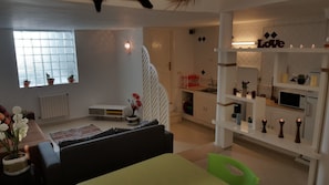 Un salon moderne comprenant un canapé, une table à manger et un coin cuisine agrémenté d’un panneau décoratif portant le mot « Love ».