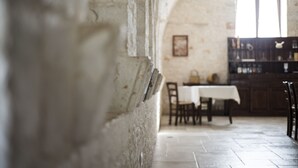 Un intérieur agrémenté d’un mur en pierre rustique, d’un coin repas avec une table et des chaises, et d’une fenêtre offrant une vue agréable.