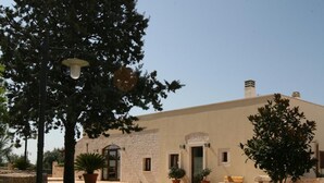 Un bâtiment doté d’une façade en pierre, d’une pelouse verdoyante et de plantes en pot.