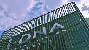 A building with a modern design featuring vertical bamboo-like structures and a prominent sign reading "DNA PHAMNETEL".
