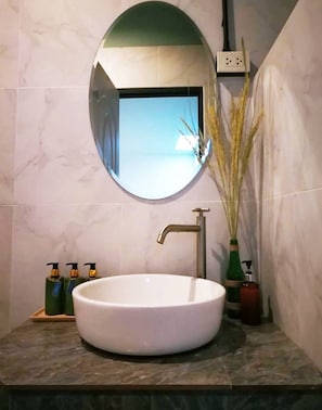 A bathroom with a round mirror, a white sink, and a vase with dried plants. - I-DNA PhanatNikhom Hometel (Phanat Nikhom)