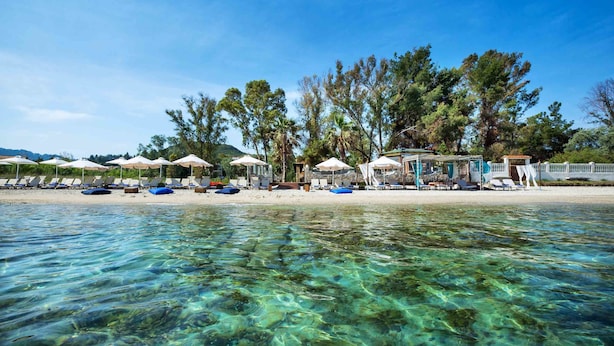 Une plage avec une eau cristalline, des parasols et des chaises longues.