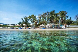 Uma praia com águas cristalinas, guarda-sóis e espreguiçadeiras.