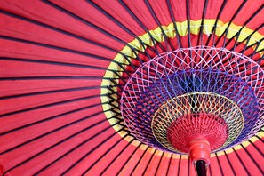 A close-up of a badminton racket with a red handle and a detailed, colorful netting pattern.