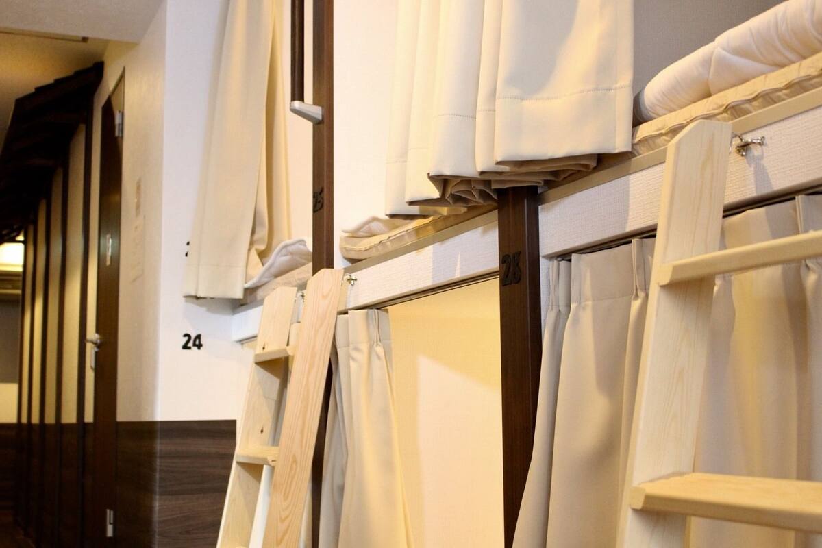 A hotel room with a wooden bed frame, white linens, and a number '24' on the wall.