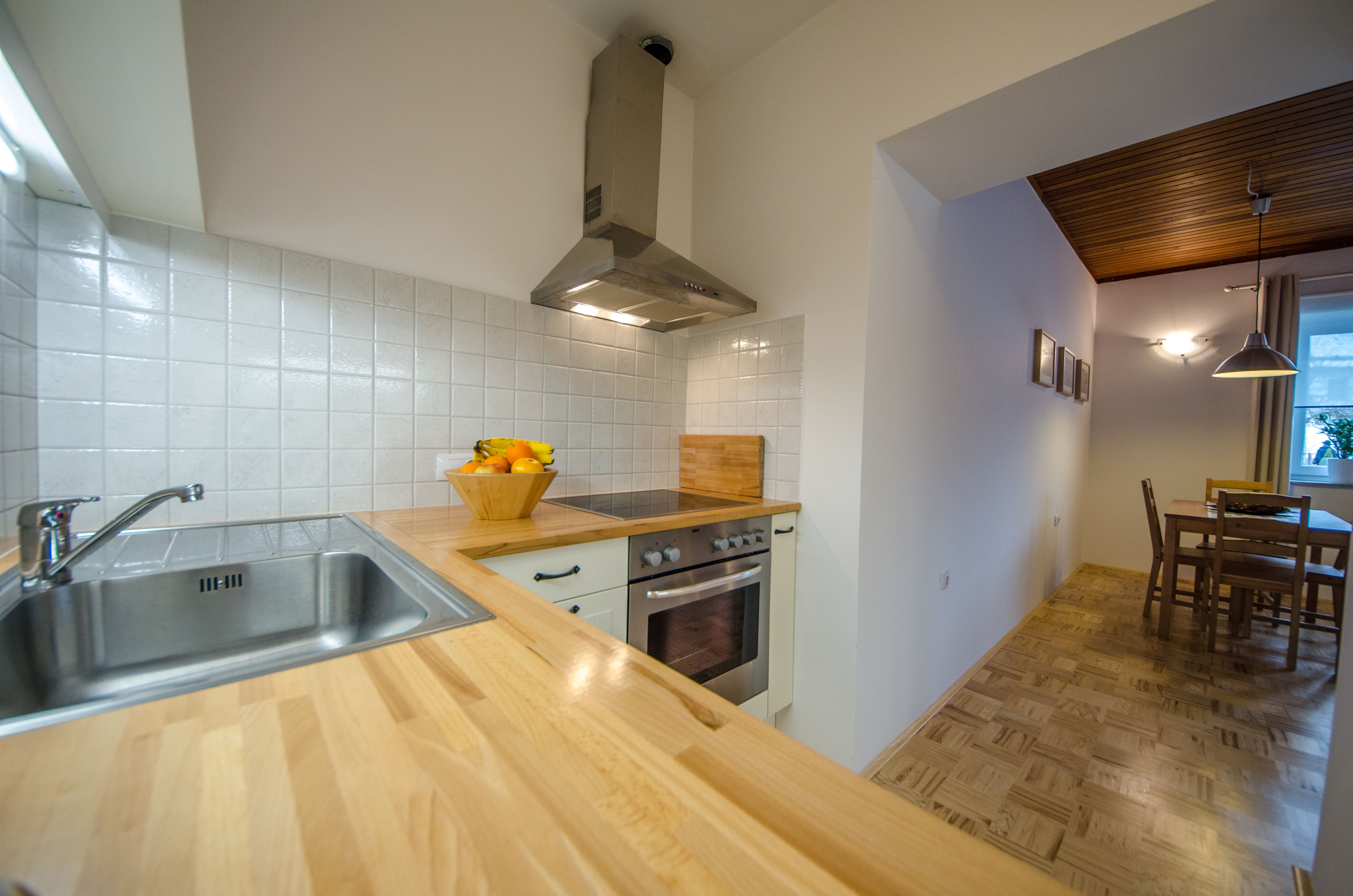 A modern kitchen with a stainless steel sink, wooden countertop, and a built-in oven.