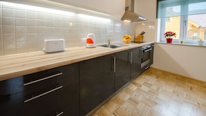 Una cocina moderna con encimera de madera, un tostador, un lavamanos y una ventana con vistas a un edificio.