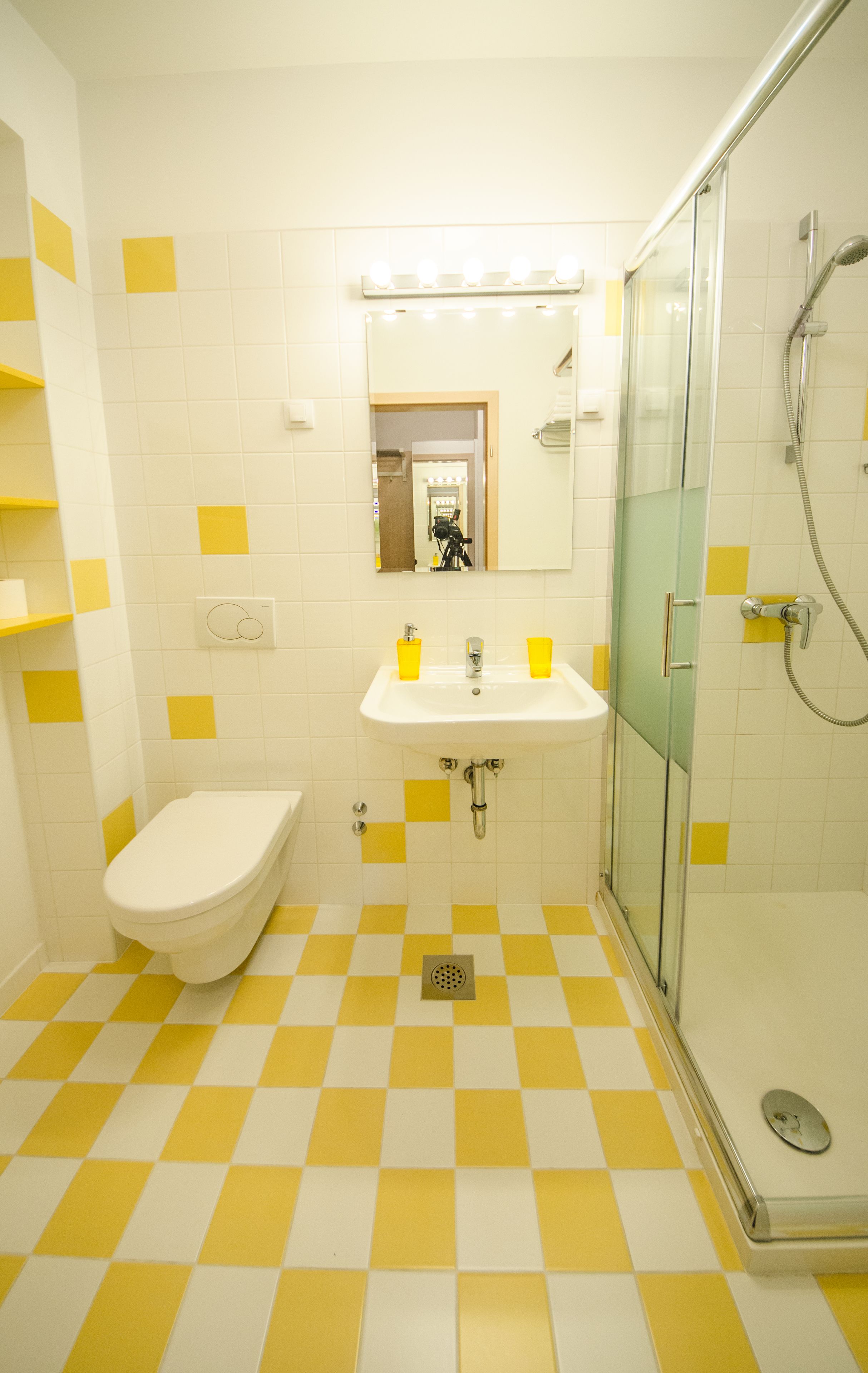 A bathroom with a checkered floor, a sink, a toilet, and a glass-enclosed shower.