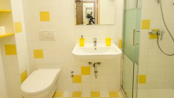 A bathroom with a checkered floor, a sink, a toilet, and a glass-enclosed shower.