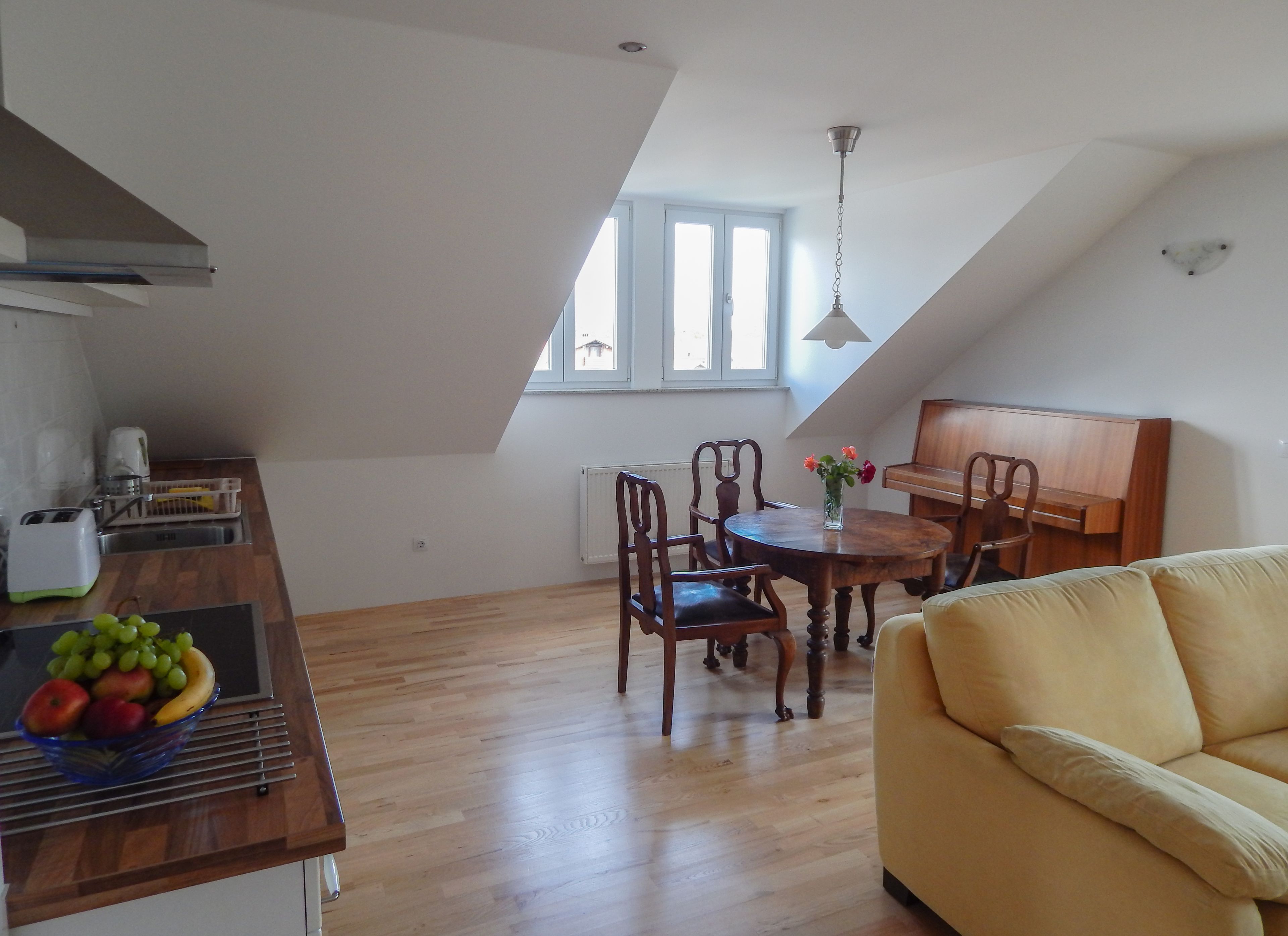 A loft-style apartment with a dining area, kitchen, and a yellow sofa.