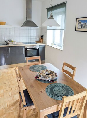 A modern kitchen with a wooden dining table, two chairs, and a decorative pine cone centerpiece. - Apartments Vila Marjetica (Bled)