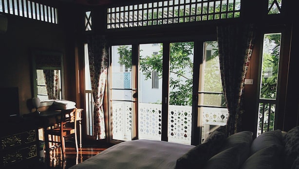 A room with a bed, a desk, and a view of greenery outside. - The White Houses (Hua Hin)