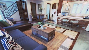 A modern living room with a dark-colored sofa set, a coffee table with a decorative centerpiece, and a patterned rug. - The White Houses (Hua Hin)