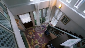A multi-level interior with a staircase, patterned carpet, and a view of greenery outside. - The White Houses (Hua Hin)