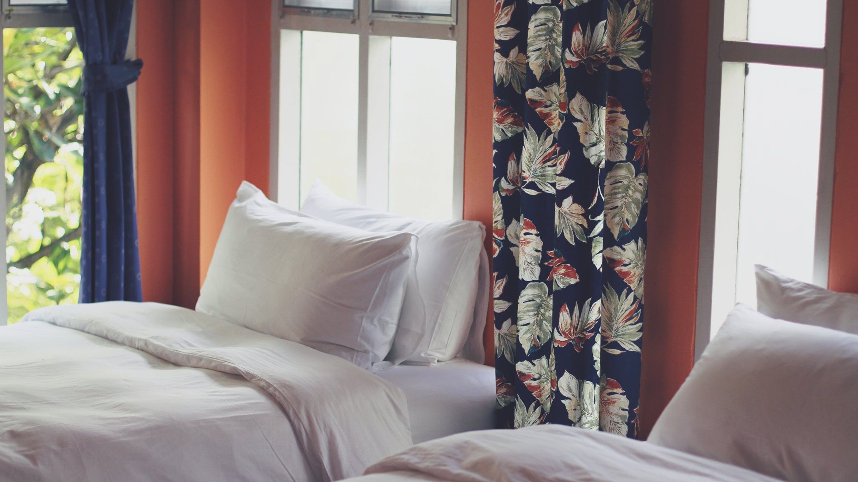 Ein Schlafzimmer mit einem Bett, weißer Bettwäsche und einem Fenster mit Vorhängen.