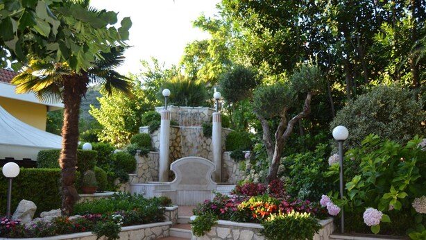 A landscaped garden with stone steps, a fountain, and various plants. - Yellow Park Hotel (Arienzo)