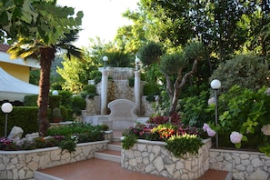 A landscaped garden with stone steps, a fountain, and various plants. - Yellow Park Hotel (Arienzo)