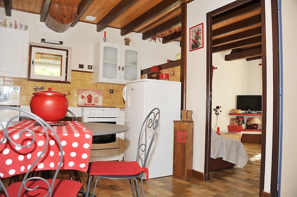 A kitchen with a red pot, a white refrigerator, and a dining table with red chairs.