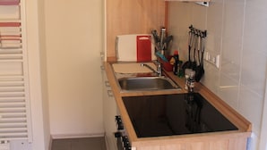 Une cuisine compacte avec des meubles en bois, un plan de travail noir et un four encastré.