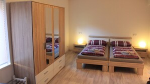 Un dormitorio con dos camas, un armario, lámparas de noche y un radiador.