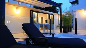 A modern outdoor seating area with lounge chairs and a glass door leading to a dining area. - MENDULA RESORT (Nin)