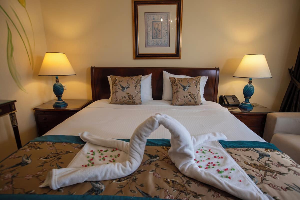 A hotel room with a large bed, two nightstands, a framed picture on the wall, and a floral bedspread.