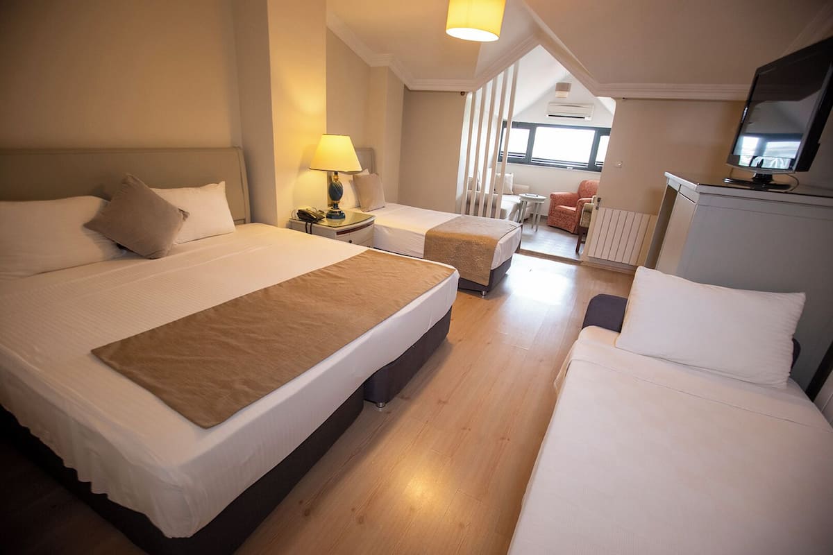 A hotel room with two beds, a desk, a chair, and a television.