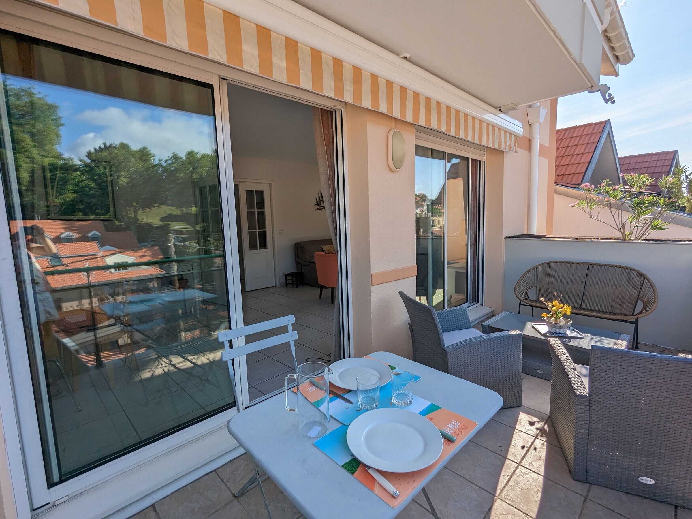 En terrasse med spiseplads, udendørs møbler og en skydedør, der fører ind i et rum.