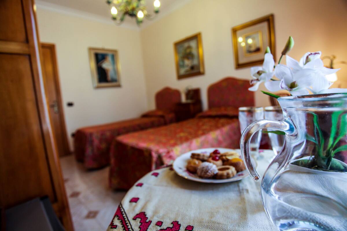 Een kamer met een bed, een tafel met gebak en een vaas met bloemen.