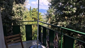 Un balcon avec un banc en bois, un pneu et une rambarde en métal.
