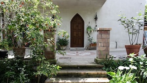 Une cour avec une porte en bois, des marches en pierre et des plantes en pot.