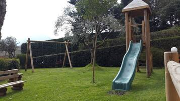 Un'area giochi con uno scivolo, altalene e una struttura in legno.