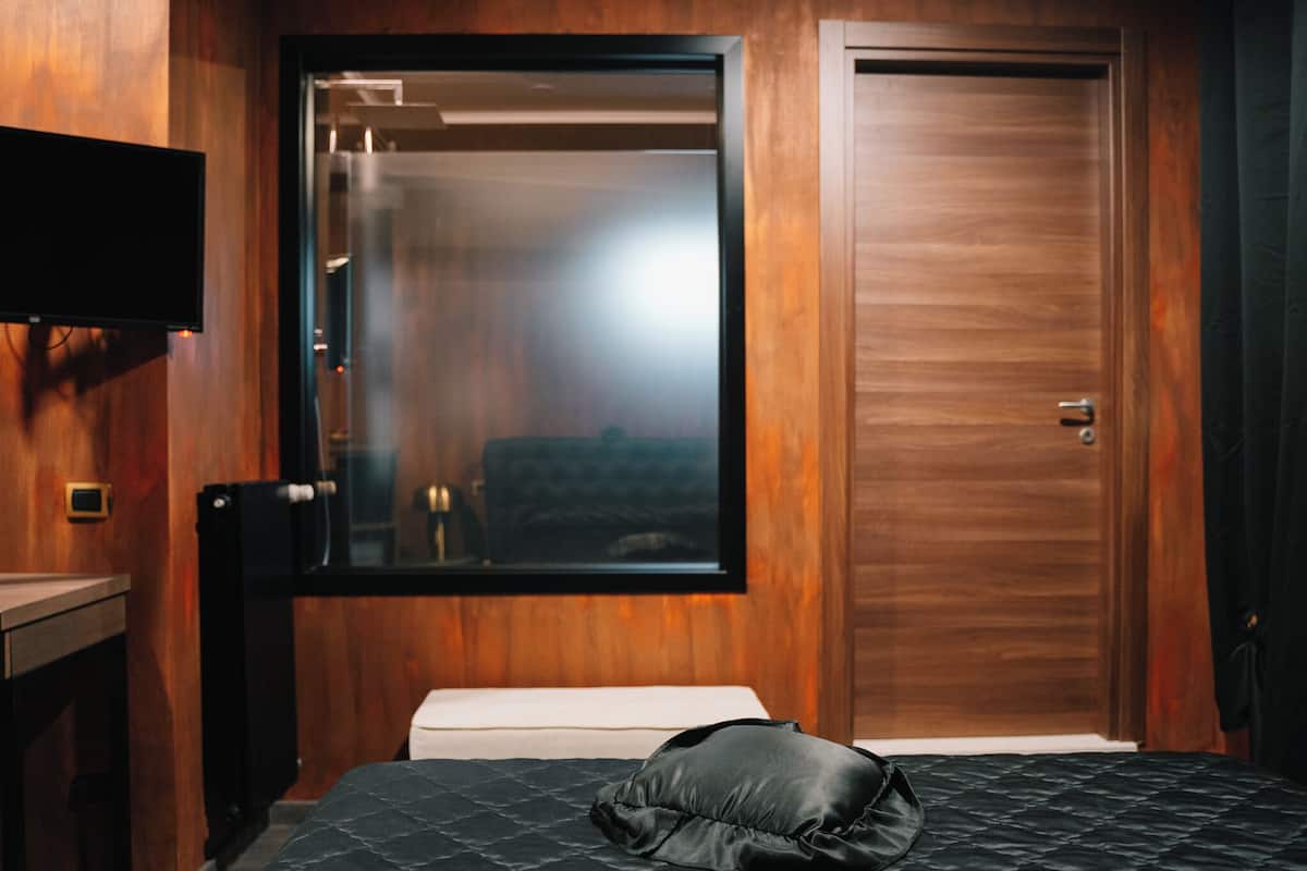 Une chambre d’hôtel avec un lit, une télévision et une porte en bois.