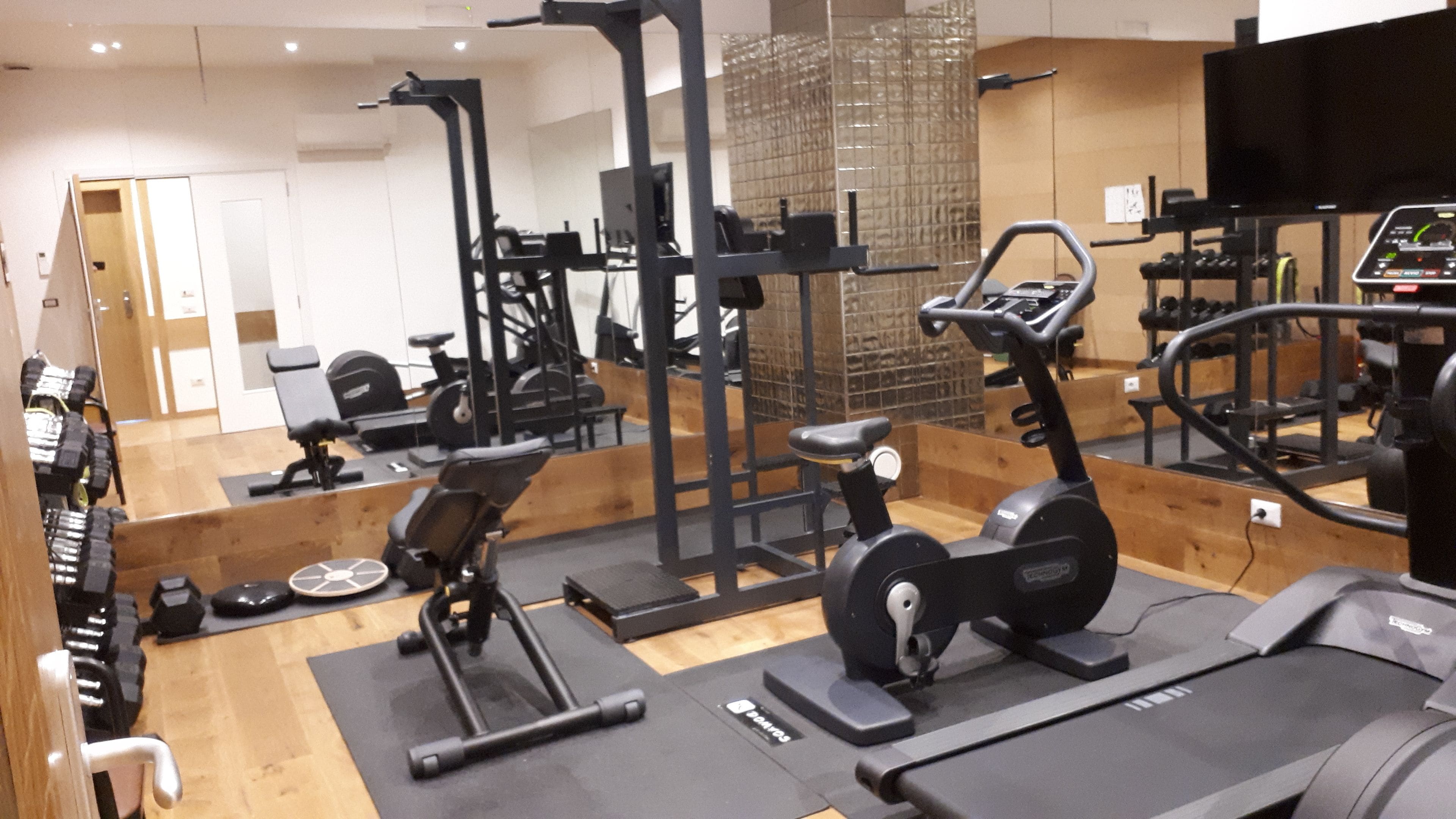 Ein Fitnessstudio mit verschiedenen Trainingsgeräten, darunter Laufbänder, Ergometer und Kraftgeräte.