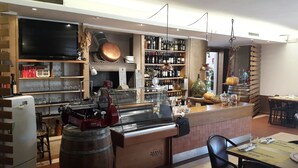 Een bar met een toonbank, planken vol flessen, een televisie en een rustieke inrichting.