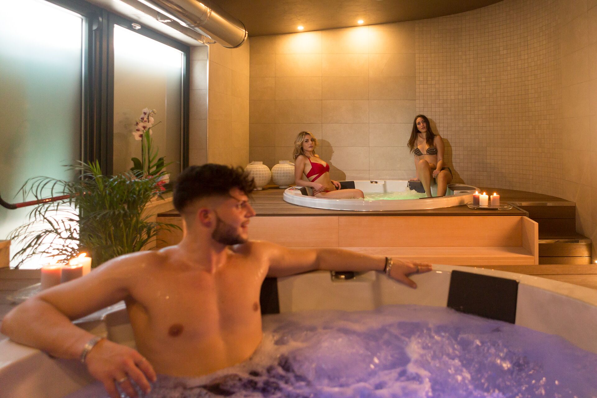 A spa area with a hot tub, a massage table, and a window with a view.
