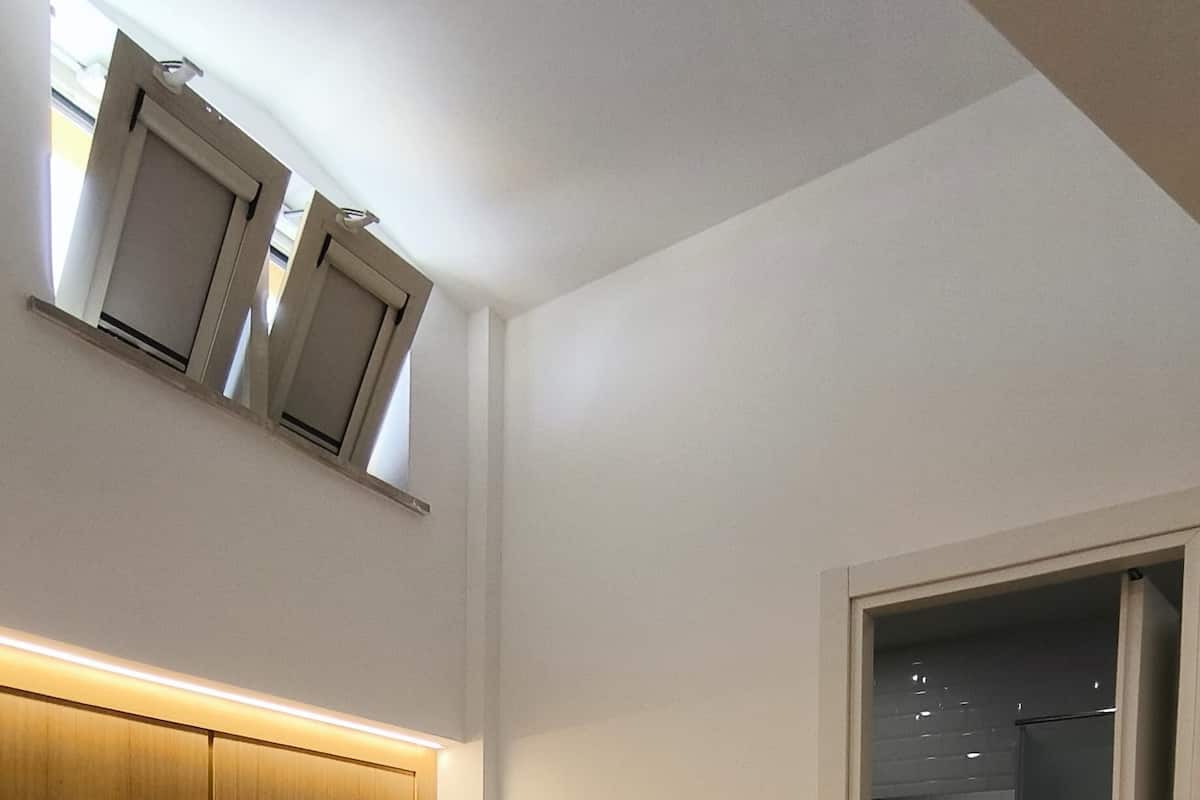 Une chambre d’hôtel moderne avec un grand lit, une tête de lit en bois et un dressing.