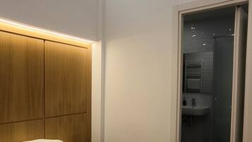 Una habitación de hotel moderna con una cama grande, cabecera de madera y un vestidor.