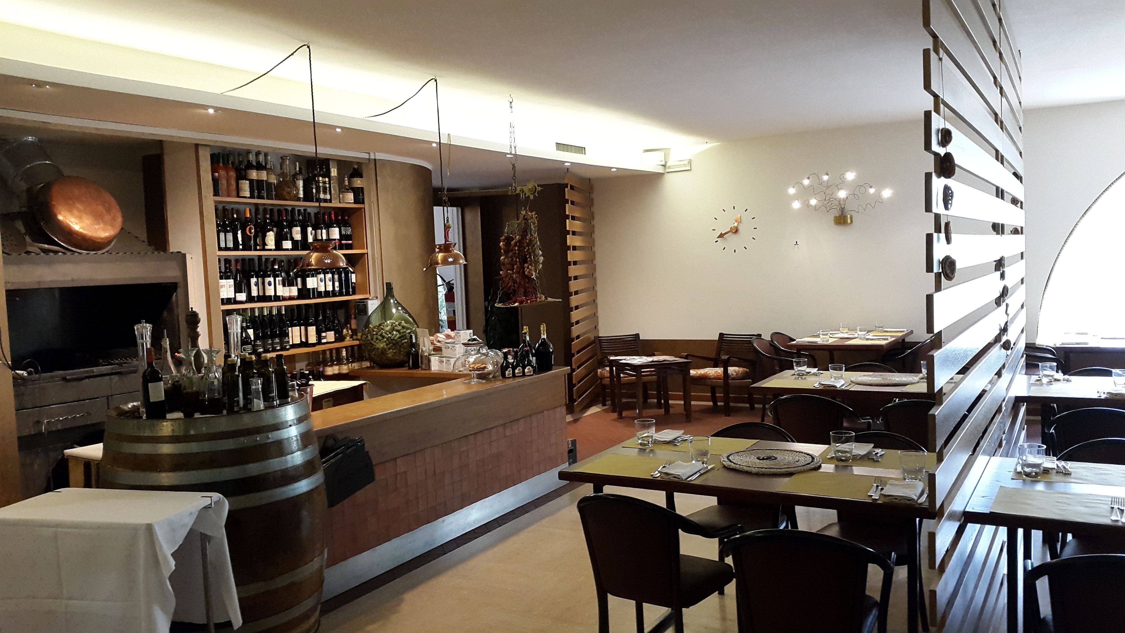 A restaurant interior with a bar area, wooden furniture, and a clock on the wall.