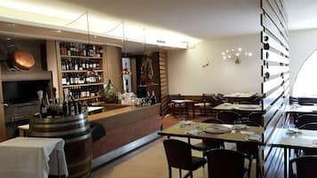 Interno di un ristorante con area bar, arredi in legno e un orologio a parete.