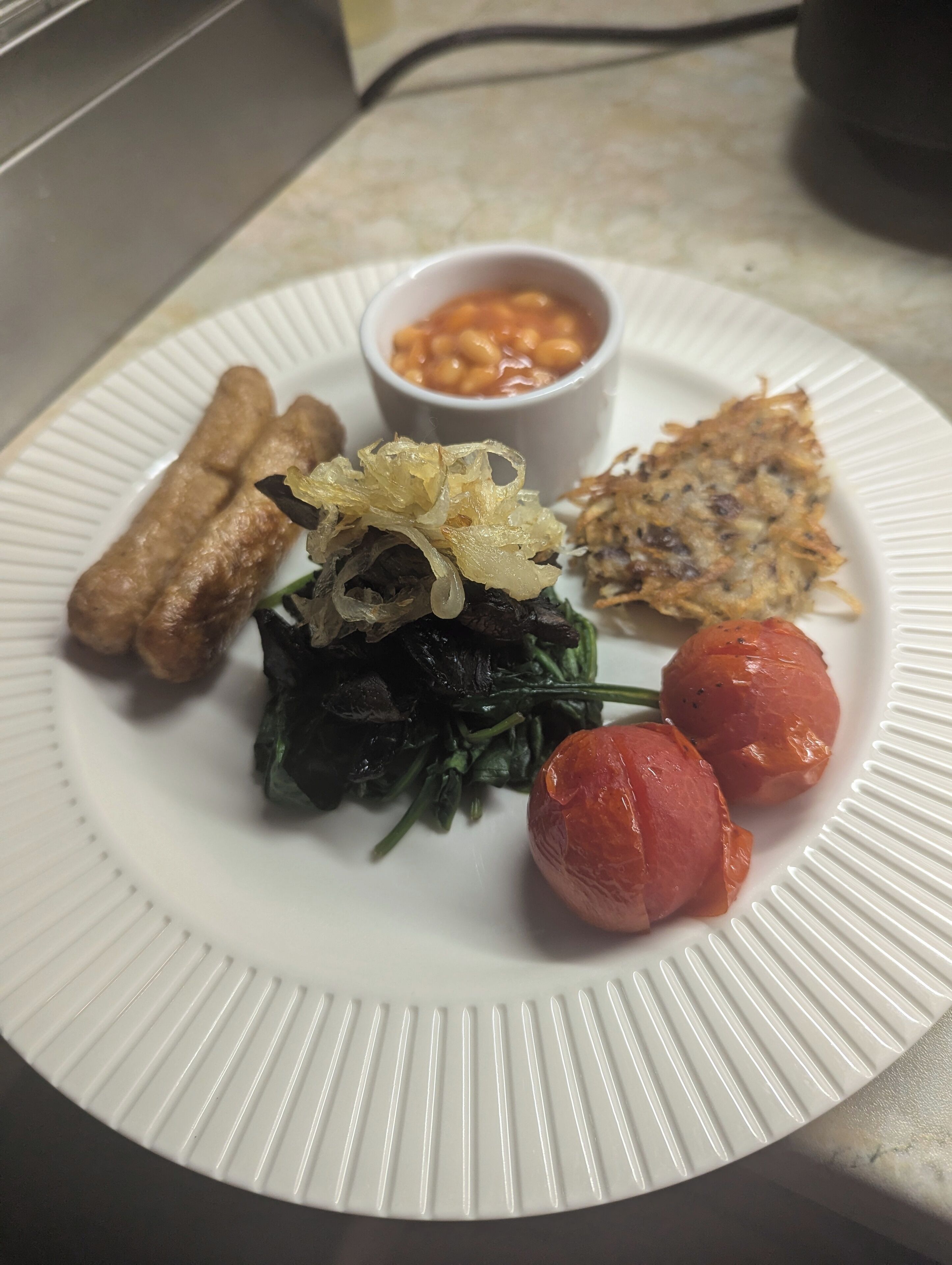 A plate with various foods including a vegetable dish, a small bowl of beans, and some fried items.