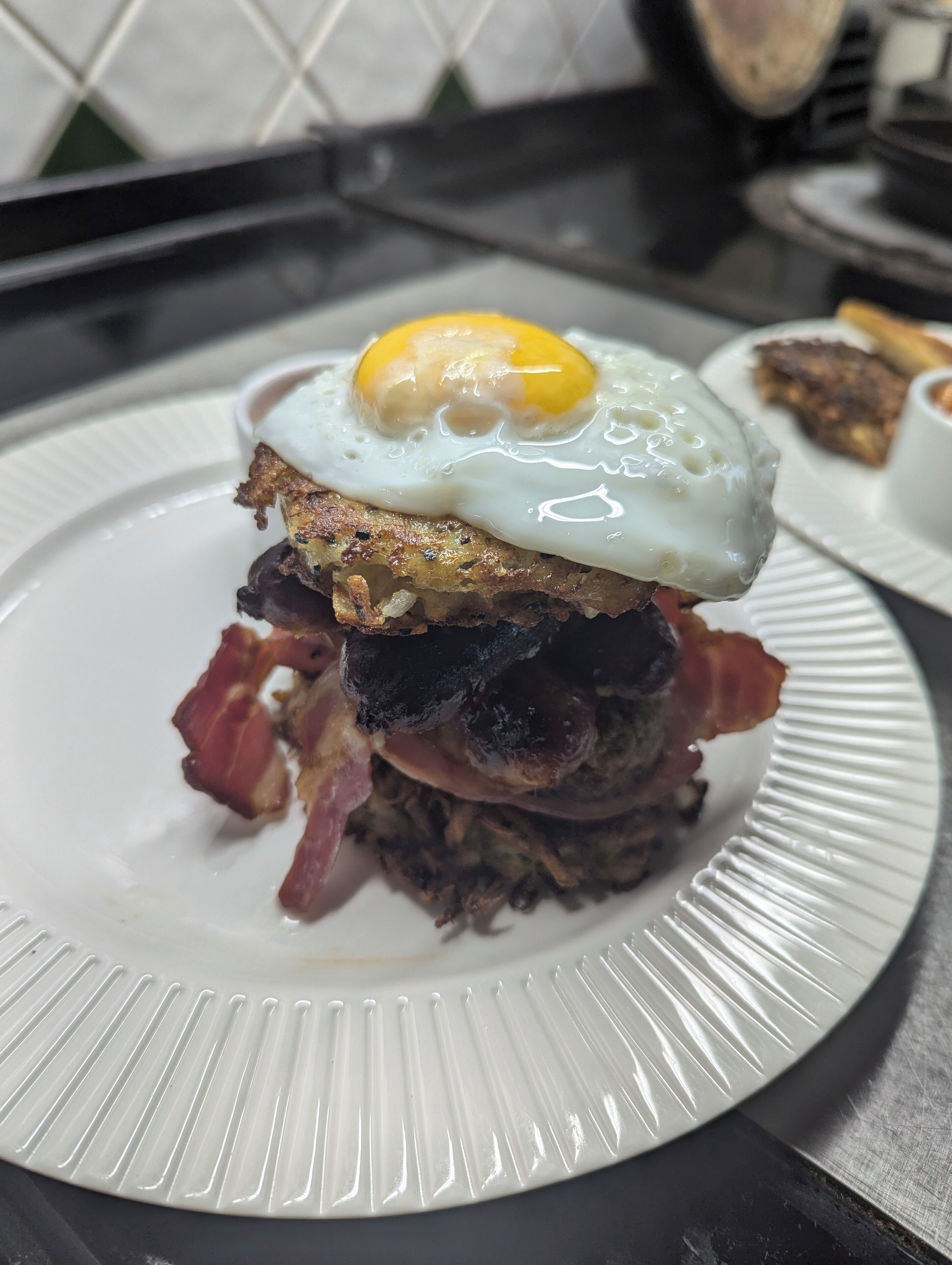 Un plato de desayuno con un huevo frito, tocino y patatas ralladas.