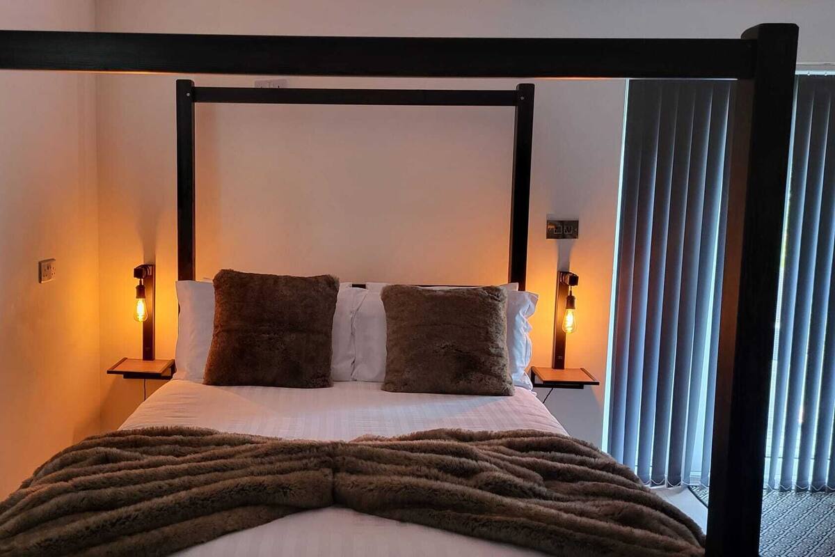 A bed with a wooden frame, two pillows, a blanket, and bedside lamps.