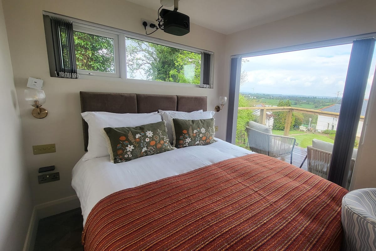 A bedroom with a bed, a window, a view of the outdoors, and a chair.