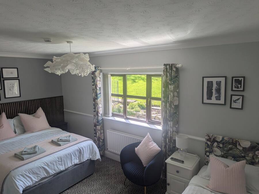 Une chambre à coucher avec un lit, une table de chevet, une chaise et une fenêtre avec des rideaux.