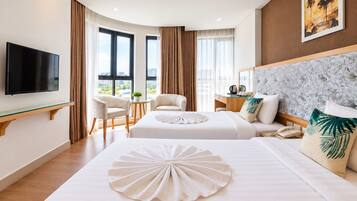 Ein Hotelzimmer mit zwei Betten, einem Flachbildfernseher, einem Schreibtisch mit Stuhl und Blick auf die Stadt.