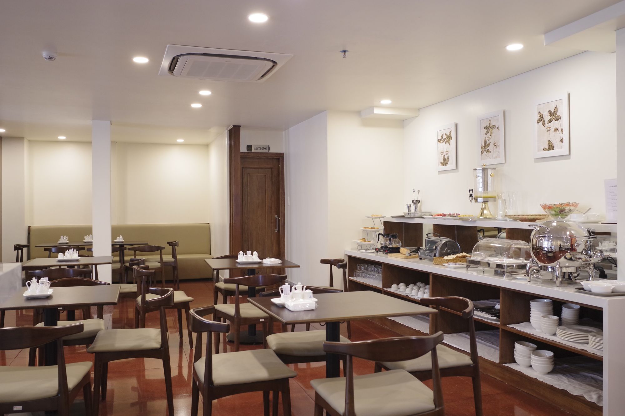 Un comedor de hotel con mesas, sillas y una barra de buffet.