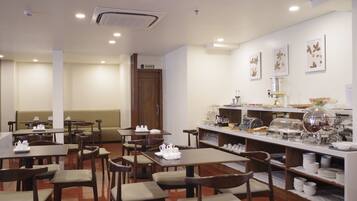 Un comedor de hotel con mesas, sillas y una barra de buffet.